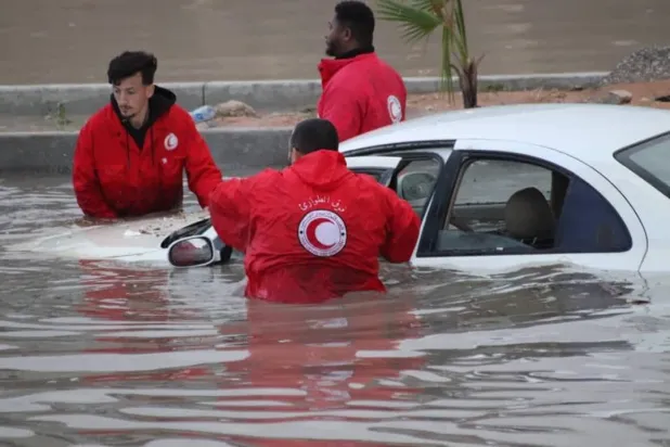 متطوعو الهلال الأحمر الليبي يحاولون إبعاد سيارة عالقة بالمياه في مدينة الزاوية (الهلال الأحمر)