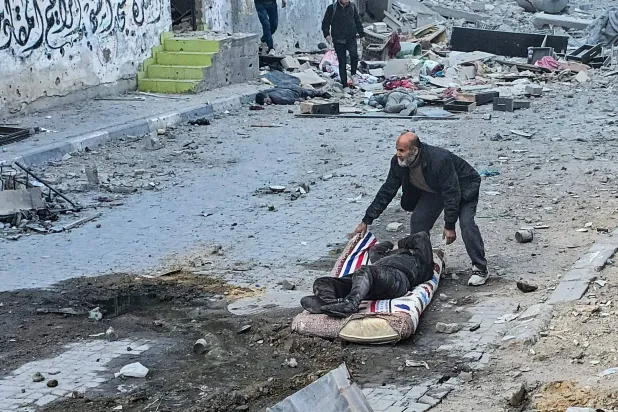 رجل يجرّ أحد المصابين نتيجة قصف إسرائيلي استهدف مستشفى كمال عدوان في بيت لاهيا شمال قطاع غزة (أ.ف.ب)