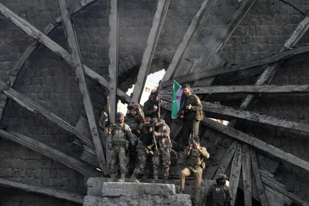 مقاتلون يرفعون علماً يمثّل فصائل سورية مسلحة وسط حلب (أ.ف.ب)