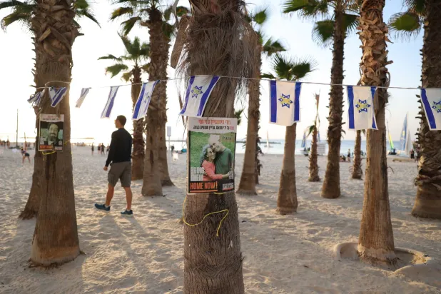 صور أسرى إسرائيليين لدى «حماس» مثبتة على جذوع أشجار على شاطئ في تل أبيب الجمعة (إ.ب.أ)