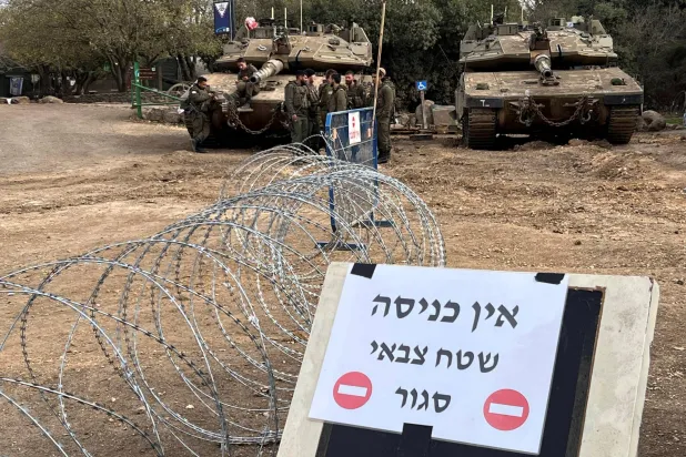 جنود إسرائيليون بجوار دبابتين في مرتفعات الجولان المحتلة بالقرب من الحدود مع سوريا يوم السبت أمام لافتة كتب عليها «ممنوع الدخول. منطقة عسكرية مغلقة» (رويترز)