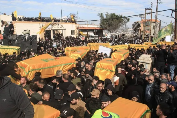 Mourners carry the flag-draped coffins of Hezbollah fighters who were killed in the recent war with Israel, during their funeral procession in the southern Lebanese village of Majdal Selm on December 6, 2024. (AFP) 