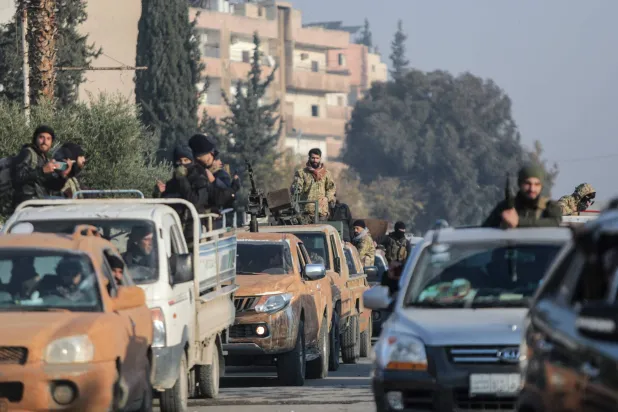 مقاتلون من الفصائل السورية يقودون سياراتهم على طول أحد شوارع مدينة حماة بوسط سوريا في 6 ديسمبر 2024 (أ.ف.ب) 
