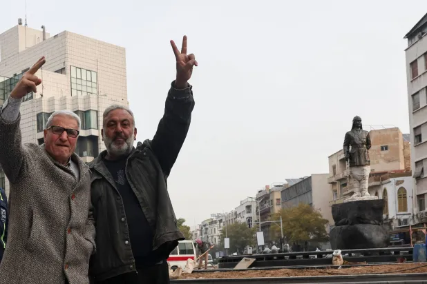 سوريون يرفعون علامة النصر في دمشق (رويترز)