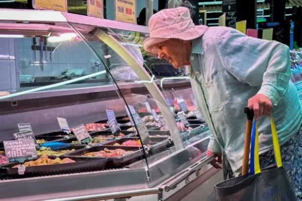 امرأة أوكرانية مسنة تنظر إلى منتجات اللحوم المختلفة في أحد المتاجر الكبرى (رويترز)