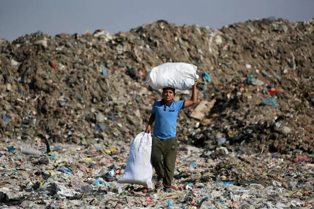 طفل يحمل أشياء تم انتشالها من مكب النفايات في خان يونس جنوب قطاع غزة (أ.ف.ب)