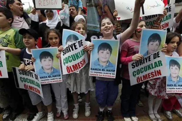 أطفال سوريون يحملون صور حمزة الخطيب (أرشيف - رويترز)