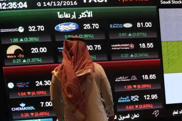 مستثمر يقف أمام شاشة تعرض معلومات سوق الأسهم السعودية «تداول» في الرياض (رويترز)