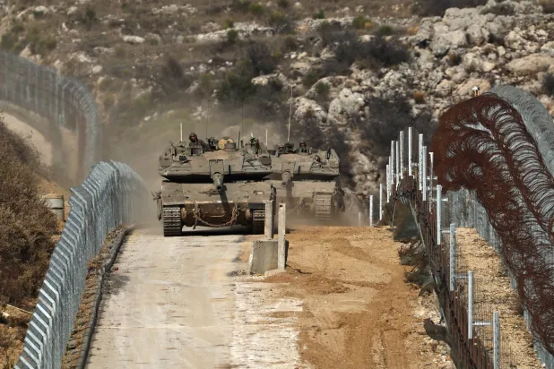 دبابات إسرائيلية تتنقل بين السياجين داخل المنطقة العازلة بين إسرائيل وسوريا (إ.ب.أ)