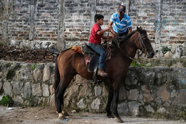 طفل يمتطي حصاناً في سوق الماشية بالسلفادور (رويترز)