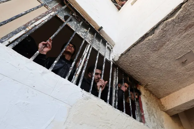 أشخاص يشاهدون عملية البحث عن معتقلين تحت الأرض في سجن صيدنايا (رويترز)