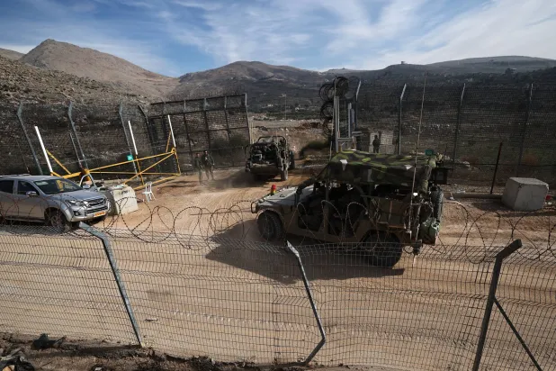 مركبة إسرائيلية تتحرك على طول الطريق باتجاه الجانب السوري من الحدود بين إسرائيل وسوريا بالقرب من قرية مجدل شمس في مرتفعات الجولان (إ.ب.أ)