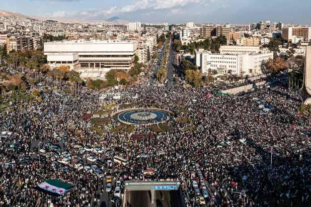 تُظهر الصورة الجوية سوريين يحتفلون بسقوط الرئيس السوري بشار الأسد بالقرب من تمثال السيف الدمشقي التاريخي بساحة الأمويين بوسط العاصمة (أ.ف.ب)