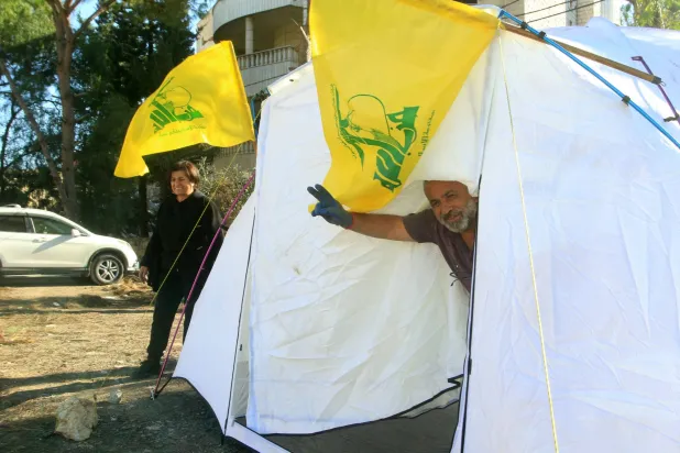 A man gestures from inside his tent, erected after lost his house during the war between Hezbollah and Israel, in the southern Lebanese city of Nabatieh on December 1, 2024. (Photo by Mahmoud ZAYYAT / AFP)