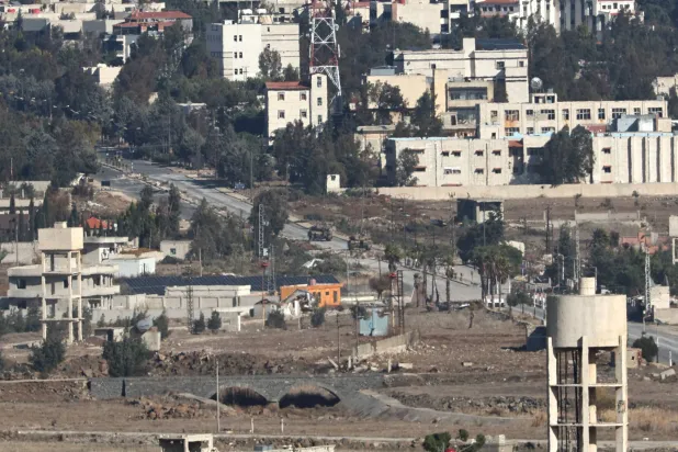 مركبات عسكرية إسرائيلية في مدينة القنيطرة السورية كما شوهدت من الجانب الإسرائيلي من مرتفعات الجولان (إ.ب.أ)