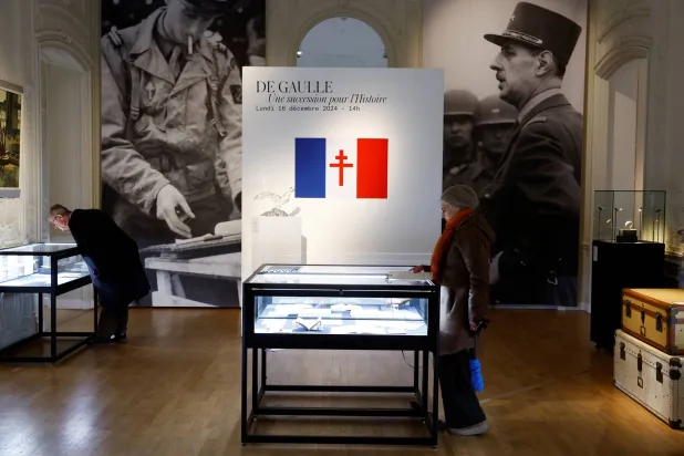 أشخاص ينظرون إلى كتابات شخصية وتذكارات للجنرال الفرنسي شارل ديغول (1890 - 1970) معروضة قبل مزاد «ديغول... إرث للتاريخ» في دار «أرتكوريال» في باريس (رويترز)