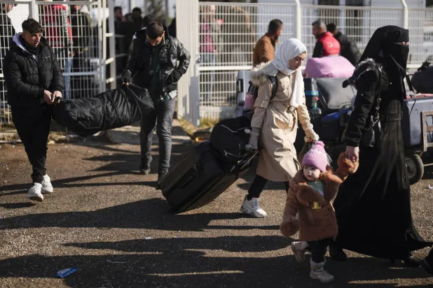 سوريون لدى عودتهم إلى بلادهم عبر معبر أونجوبينار الحدودي قرب مدينة كيليس جنوبي تركيا أمس (أ.ب)