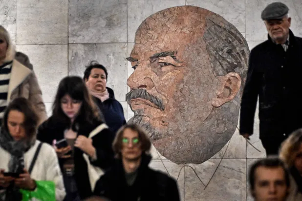يمر ركاب بجوار صورة لمؤسس الاتحاد السوفياتي فلاديمير لينين في محطة مترو بموسكو في نوفمبر 2023 (أ.ف.ب)