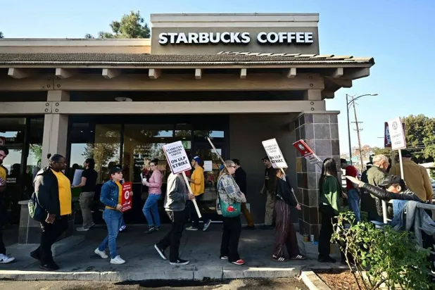 Starbucks workers hold signs as they picket during a strike in front of a Starbucks to demand collective bargaining agreements in Burbank, California on December 20, 2024. (AFP)