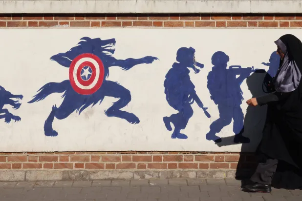 امرأة إيرانية تمشي أمام لوحة جدارية على حائط السفارة الأميركية السابقة في طهران (أ.ف.ب)