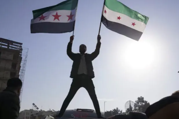 A man holds the Syrian opposition flag as they celebrate after Syria's army command notified officers on Sunday that President Bashar al-Assad's 24-year authoritarian rule has ended - Aleppo, Syria - AFP
