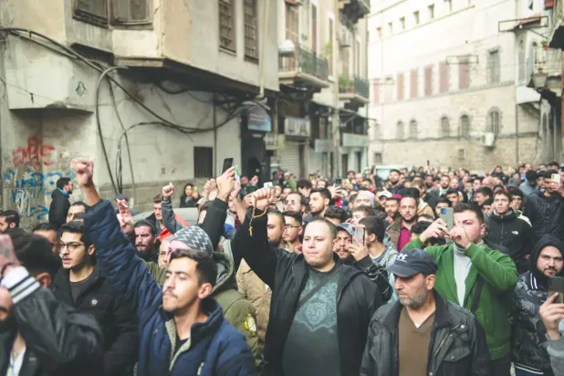 Suriyeli Hıristiyanlar dün Şam'ın Bab Tuma mahallesinde, Hama vilayetinin es-Sukaylebiyye kasabasında maskeli kişiler tarafından bir Noel ağacının yakılmasını protesto etmek için bir gösteri düzenledi. (EPA)