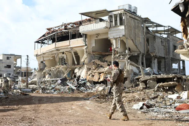 عنصر من الجيش اللبناني يسير بالقرب من الأنقاض في الخيام (رويترز)