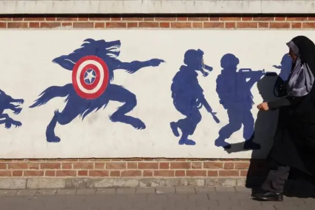 An Iranian woman walks by the former US embassy in Tehran. (AFP) 