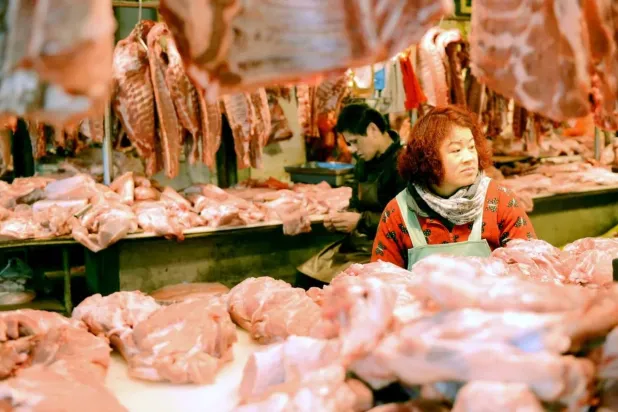 بائعة تنتظر المشترين في أحد متاجر اللحوم بمقاطعة قينغداو الصينية (أ.ف.ب)