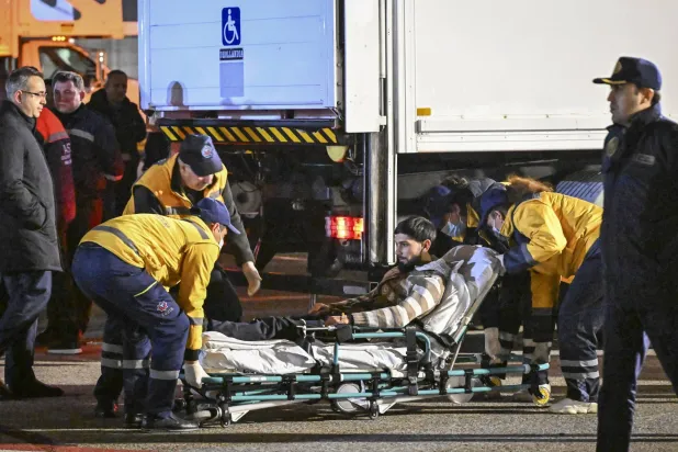 مسعفون ينقلون جريحاً وصل إلى مطار باكو بعد تحطم الطائرة الأذربيجانية (إ.ب.أ)