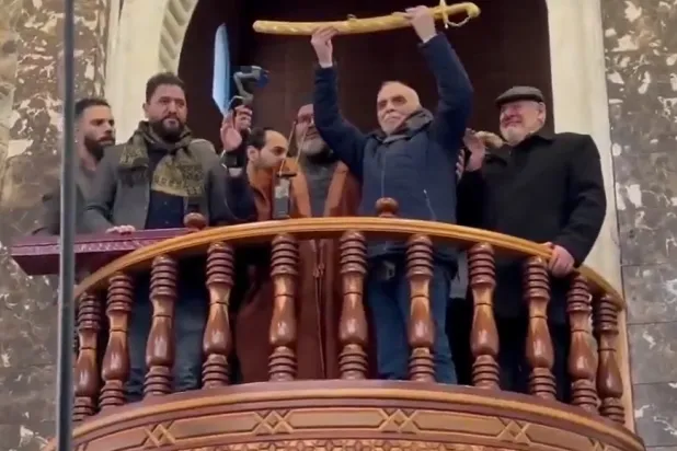 لقطة من فيديو متداول على مواقع التواصل الاجتماعي تُظهر رغيد الططري وهو يحمل سيفاً ذهبياً في حماة (إكس)