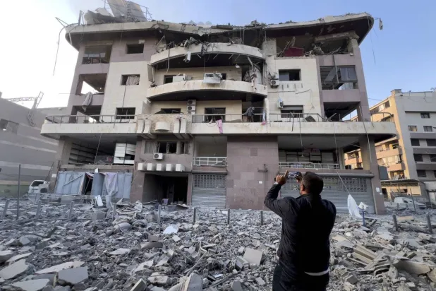 مواطن يصوّر بيته الذي تعرض للقصف في الضاحية الجنوبية لبيروت (أ.ب)
