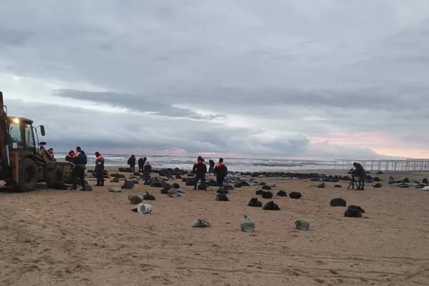 عناصر من وزارة الطوارئ الروسية يعملون على تنظيف شاطئ لوَّثه تسرُّب نفطي في القرم (إ.ب.أ)