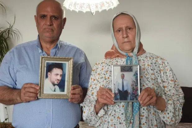 سهام وعصام صيام يرفعان صور لابنهما وسام الذي قضى في مجزرة التضامن بدمشق عام 2013 (أ.ب)