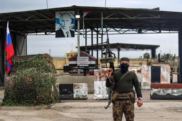 Heyet Tahrir El Şam'a bağlı bir grup üyesi dün Lazkiye vilayetindeki Rus Hmeymim üssünün girişi önünde duruyor (AFP)