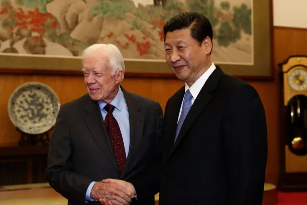 الزعيم الصيني شي جينبينغ يصافح الرئيس الأميركي الأسبق جيمي كارتر خلال اجتماع في بكين، 13 ديسمبر 2012 (أ.ب)