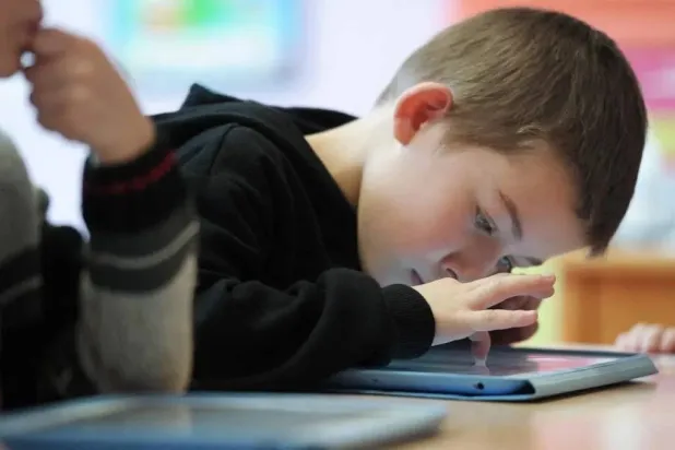 طفل يستخدم جهازاً لوحياً (أ.ف.ب)