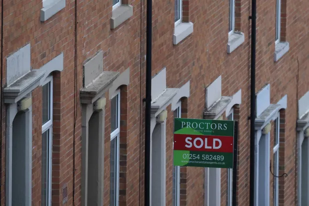 لوحة وكيل عقارات معروضة خارج منزل في شارع سكني في بلاكبيرن (رويترز)