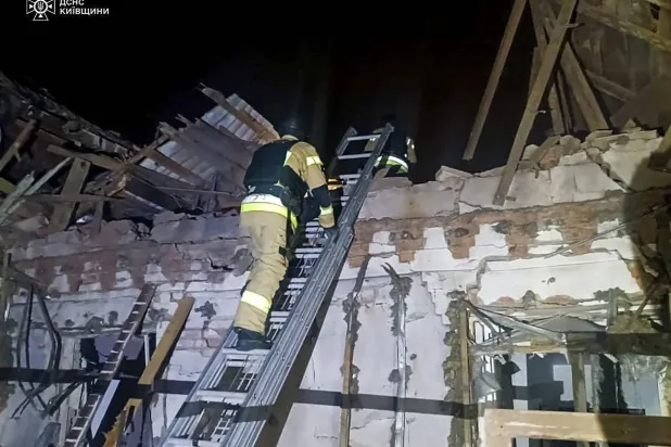 رجال إنقاذ أوكرانيون في موقع هجوم مسيّرة روسية بكييف (إ.ب.أ)