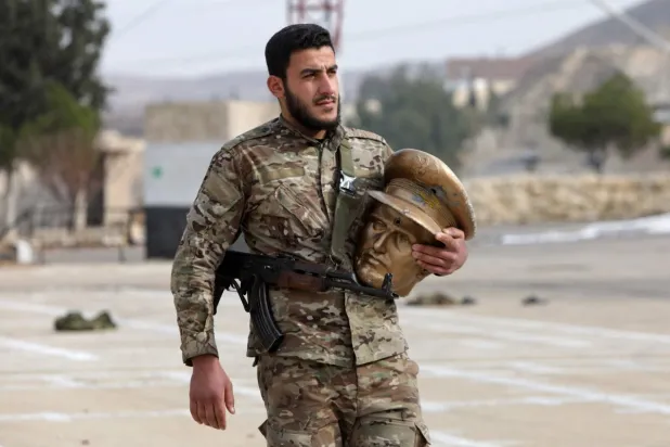 مقاتل يحمل رأس تمثال لباسل أكبر أبناء الرئيس الأسبق حافظ الأسد في معسكر مهجور للحرس الجمهوري قرب دمشق أمس (أ.ف.ب)