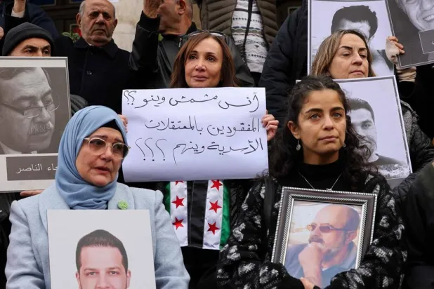 People hold portraits of missing relatives during a protest outside the Hijaz train station in the capital Damascus on December 27, 2024, calling for accountability for the perpetrators of crimes in Syria. (AFP)