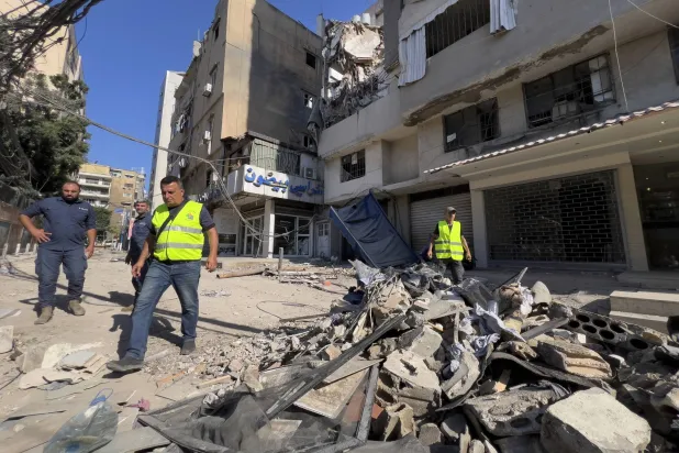 FILE - Municipality workers pass by debris of damaged buildings that were hit by an Israeli airstrike on Tuesday evening in the southern suburbs of Beirut, Lebanon, Wednesday, July 31, 2024.  (AP Photo/Hussein Malla, File)