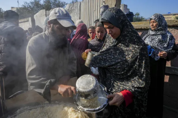 فلسطينيون يجمعون الطعام المتبرع به في مركز توزيع أغذية في دير البلح وسط قطاع غزة، 2 يناير 2025 (أ.ب)