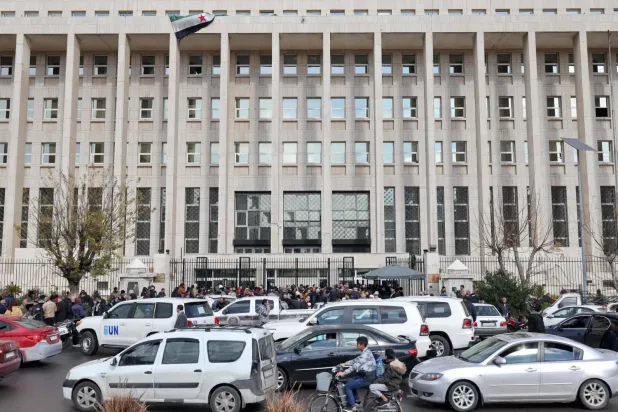 Suriye Merkez Bankası'nın ana binasının önünde insanlar karaborsadan daha düşük fiyatlarla ABD doları alışverişi yapmaya çalışıyor... Şam, 30 Aralık 2024 (AFP)