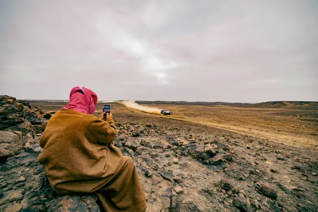 مواطن سعودي يوثق بعدسة جواله مرور أحد المتسابقين (الشرق الأوسط)