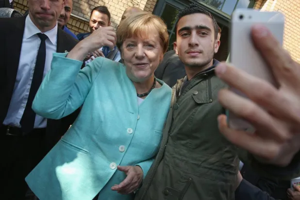 السوري ـ الألماني أنس معضماني يلتقط صورة مع المستشارة الألمانية السابقة أنجيلا ميركل قبل 12 عاماً (غيتي)
