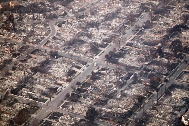 PACIFIC PALISADES, CALIFORNIA - JANUARY 09: In an aerial view, an emergency vehicle (C) drives past destroyed homes as the Palisades Fire continues to burn on January 09, 2025 in Pacific Palisades, California. Mario Tama/Getty Images/AFP