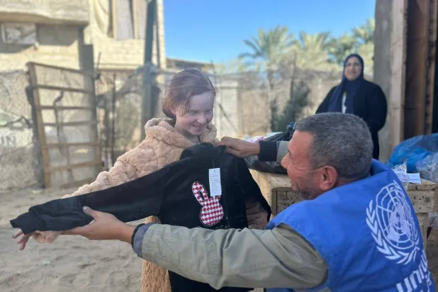موظف تابع لمنظمة «أونروا» في أثناء توزيع ملابس شتوية في خان يونس (أونروا)