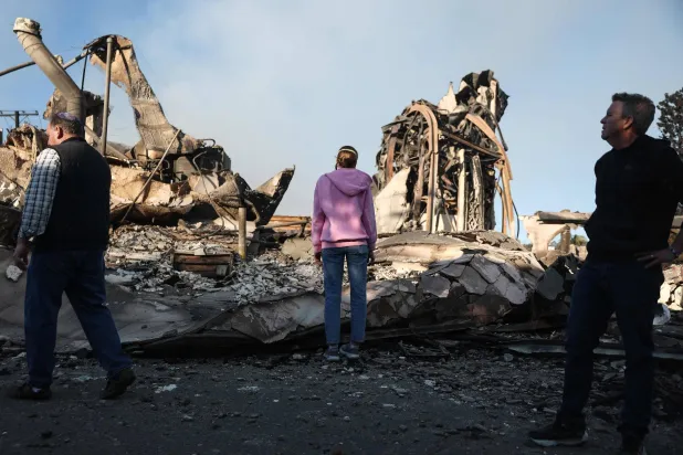 مقيمون يتفقدون الدمار الذي ألحقته الحرائق بكنيسة في «باسيفيك باليسايدز» 11 يناير (أ.ف.ب)