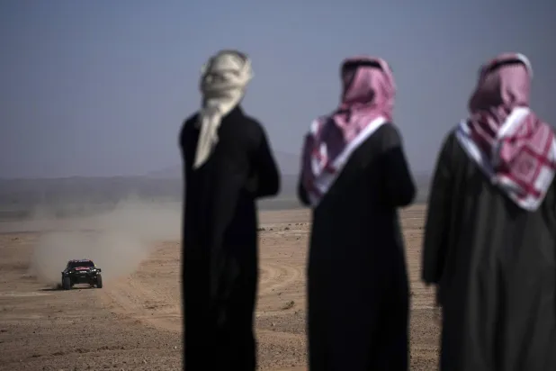 مشجعون سعوديون يراقبون مرور إحدى سيارات الرالي (أ.ب)